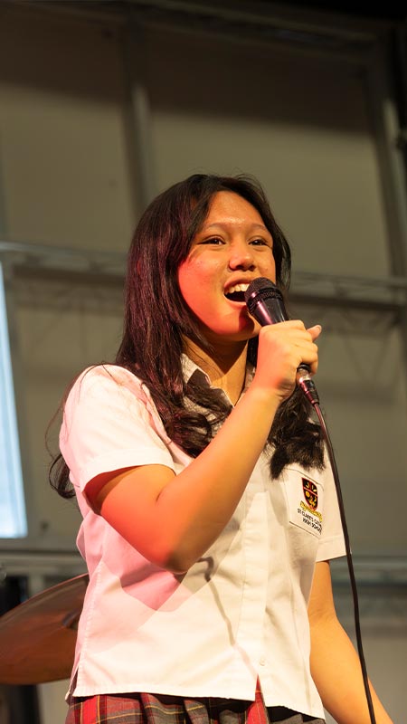 St Clare's Hassall Grove student singing into microphone