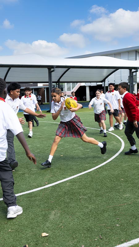 Students playing AFL on school sports field