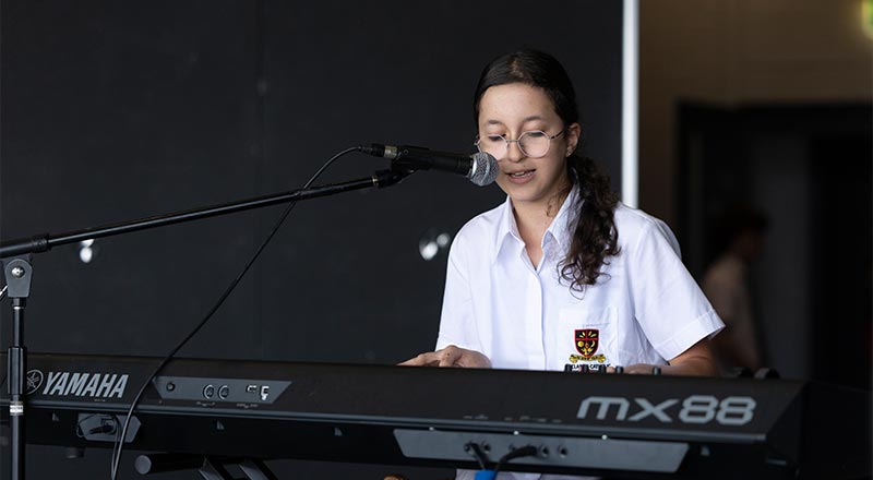 St Clare's Hassall Grove student playing piano and singing at open mic
