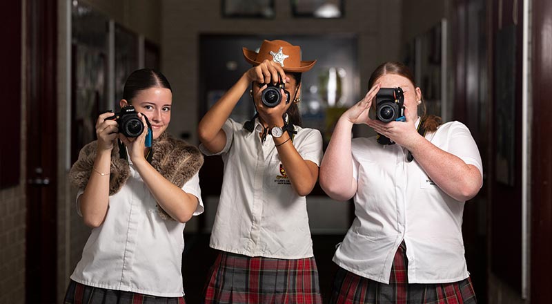 Three St Clare's photography students posing to take a photo