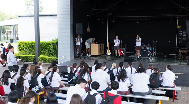 St Clare's Students sitting in Amphitheatre and watching two singers