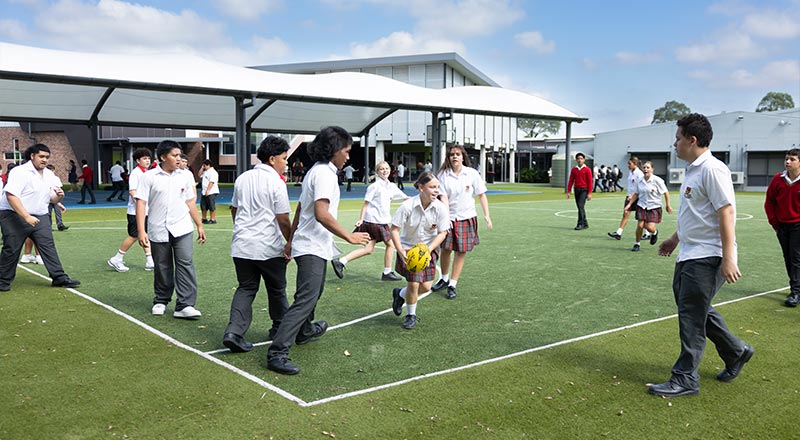 Outdoor sporting field at St Clare's Hassall Grove, students playing soccer.