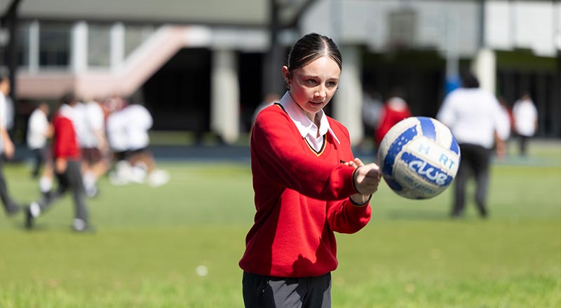 St Clare's Hassall Grove student playing netball in school netball court