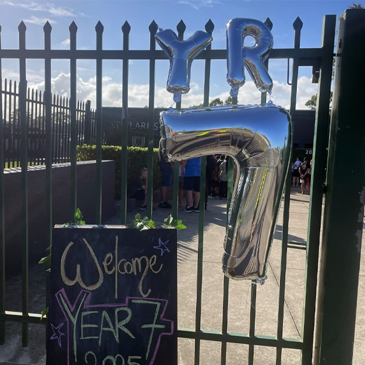 Front school gate. There are balloons which spell out Yr 7, and there is a sign with Welcome Year 7 written on it